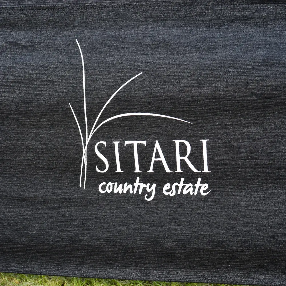 Branded black shade net fencing with white Sitari Country Estate logo installed in front of a commercial building.